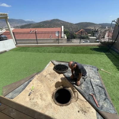 אדם עובד על צינור ביוב בחצר עם כלים