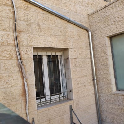 צינור מתכת על קיר אבן ליד חלון