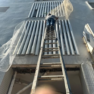 אדם על סולם מתקין רשת על בניין