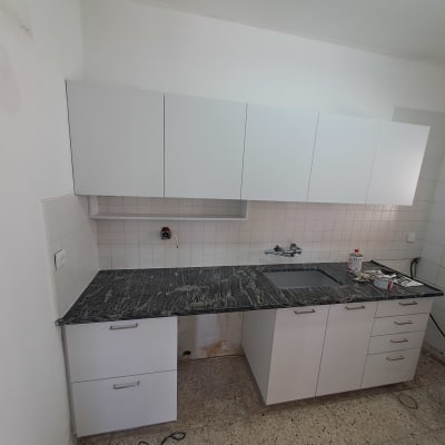 מטבח עם ארונות לבנים ומשטח עבודה כהה