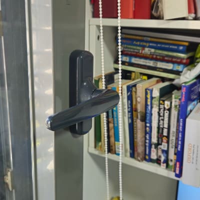 ידית חלון ליד מדף עם ספרים ותיקיות