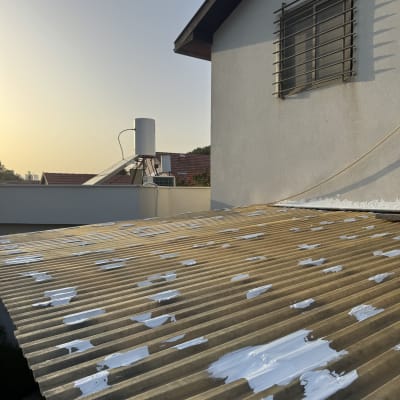 גג עם תיקוני צבע לבנים על לוחות גלי