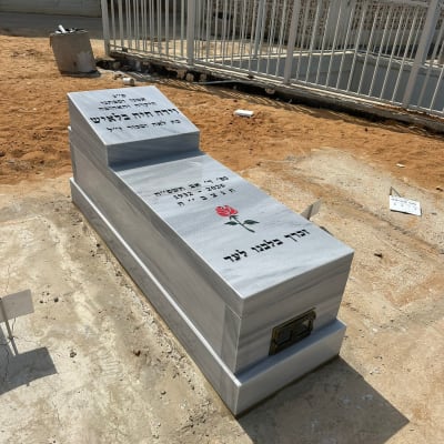 מצבה עם כיתוב בעברית ופרח חקוק