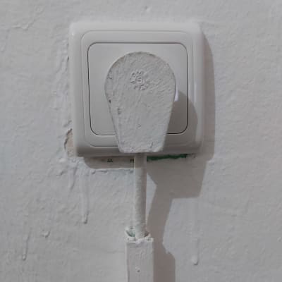 מתג חשמל עם כיסוי צבוע בלבן על קיר