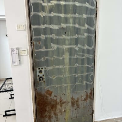 דלת מתכת חלודה עם סימני שחיקה ותיקון