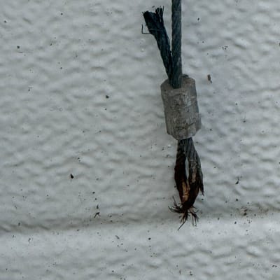 כבל מתכת קרוע על רקע קיר לבן