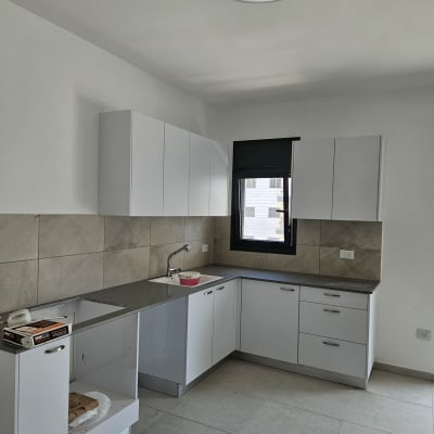 מטבח עם ארונות לבנים וכיור נירוסטה