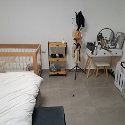 חדר מסודר עם עריסה, שידת איפור ומעמד כובעים