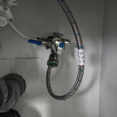 צינור מים עם ברז מתכת מתחת לכיור