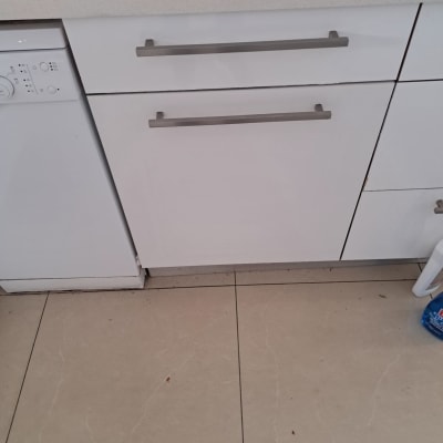 כיור מטבח עם ארונות לבנים ומדיח כלים