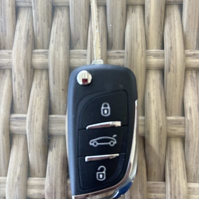 מפתח רכב עם שלושה כפתורים על רקע עץ