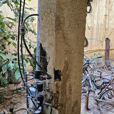 עמוד בטון עם צינורות ומדי מים בחצר