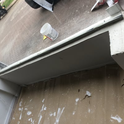 דלי צבע לבן על רצפה עם קרטון מוכתם בצבע