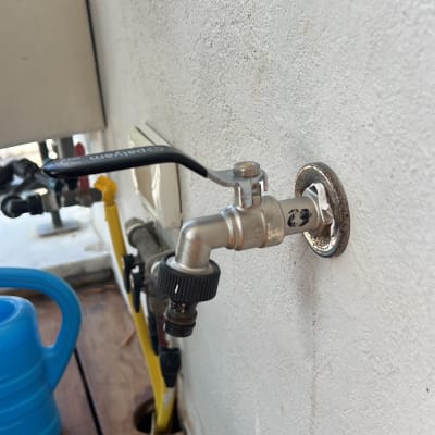 ברז מים מותקן על קיר עם צינור צהוב