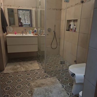 חדר אמבטיה עם מקלחון זכוכית ורצפת אריחים מעוצבת