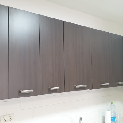 ארונות מטבח כהים עם ידיות מתכת על קיר לבן