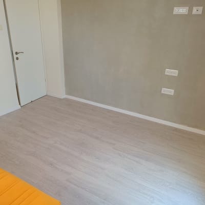 חדר עם פרקט עץ בהיר וקיר אפור