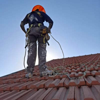עובד על גג רעפים עם ציוד בטיחות
