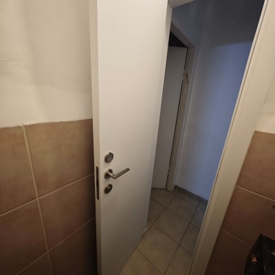 דלת לבנה פתוחה עם ידית מתכת בחדר אמבטיה