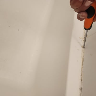 יד מחזיקה מברג בודקת איטום באמבטיה