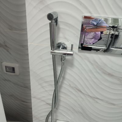 ברז מקלחת עם צינור מתכת על קיר לבן