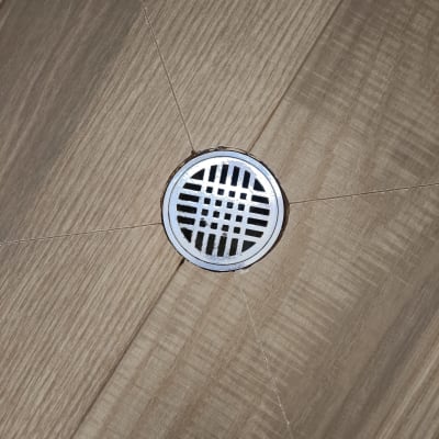 רצפת עץ עם פתח ניקוז עגול במרכז