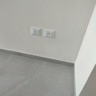 שקע חשמל ומתג על קיר צבוע בלבן