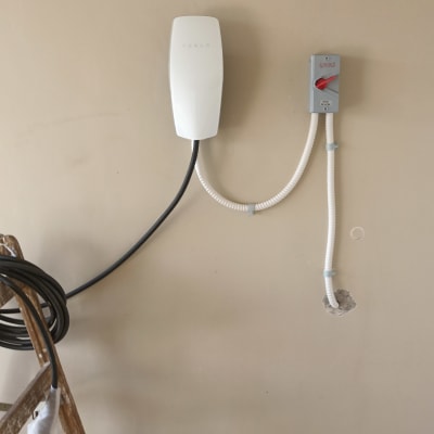 מטען טסלה מותקן על קיר עם כבלים ולוח חשמל