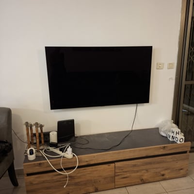 טלוויזיה מותקנת על קיר עם כבלים ויחידת מדפים מעץ