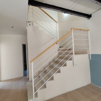 מעקה מתכת לבן עם ידית עץ במדרגות