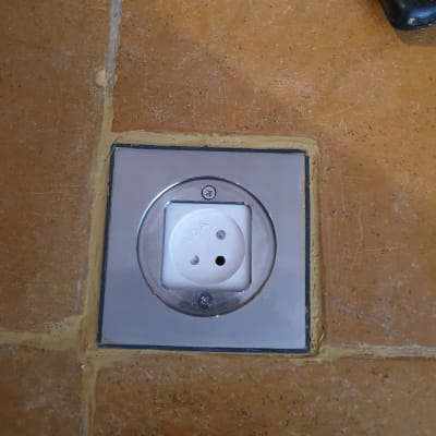 שקע חשמלי מותקן בקיר אריחים חומים