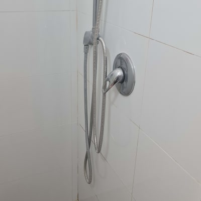 מקלחת עם ראש מקלחת על קיר אריחים לבנים