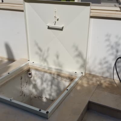 מסגרת מתכת לבנה עם מכסה פתוח על רצפה