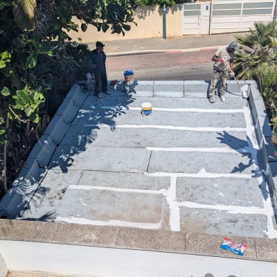 שני אנשים אוטמים גג עם חומר איטום לבן