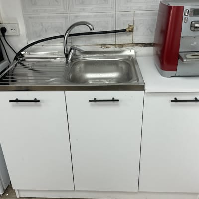 כיור נירוסטה עם ברז ומכונת קפה אדומה
