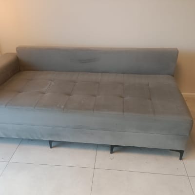 ספה אפורה עם כתמים קלים על הרצפה