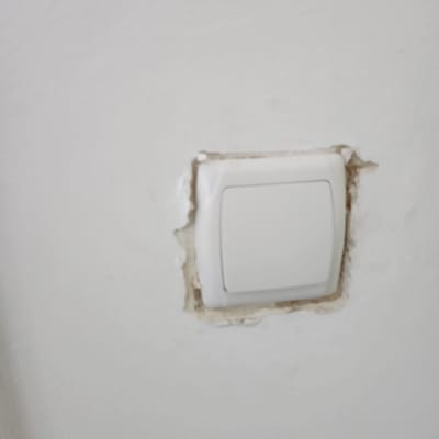 מתג חשמל בקיר עם טיח מתקלף סביבו