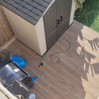 מחסן גינה עם צינור מים וכלים על רצפת עץ