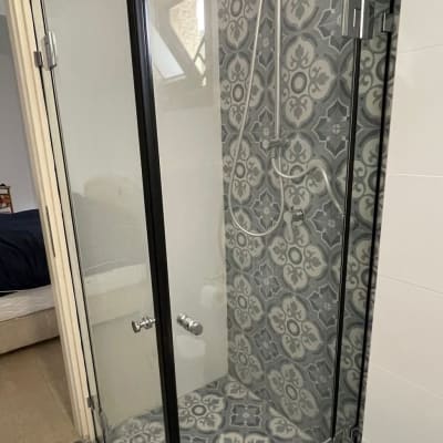 מקלחון זכוכית עם ראש מקלחת עגול וקיר מעוצב