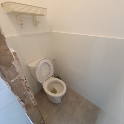 אסלה פתוחה בחדר שירותים עם מדף מעל