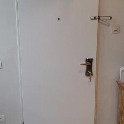 A white door with a metal handle and a peephole.