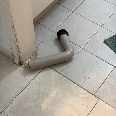 צינור פלסטיק על רצפת אריחים ליד ארון