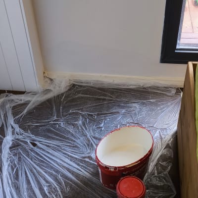 דלי צבע לבן על יריעת ניילון ברצפה