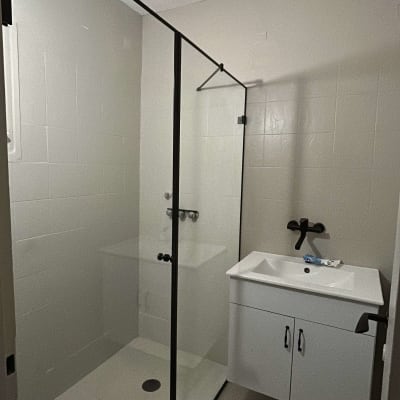 מקלחון זכוכית עם כיור לבן וברז שחור