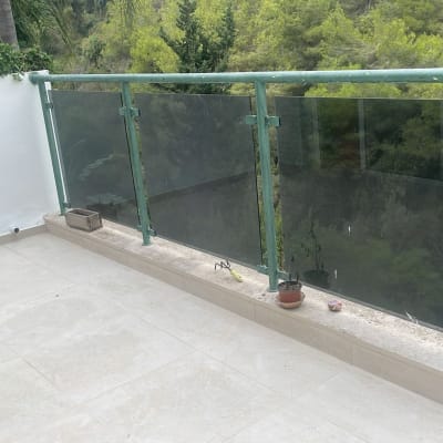 מרפסת עם מעקה זכוכית, עציצים וכלי עבודה קטנים