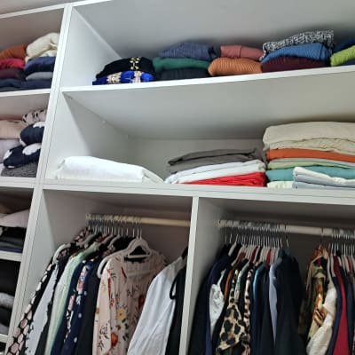 בגדים מקופלים ומסודרים בארון בגדים לבן