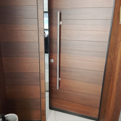 דלת כניסה מעוצבת בחיפוי עץ עם ידית משיכה מנירוסטה וצילינדר