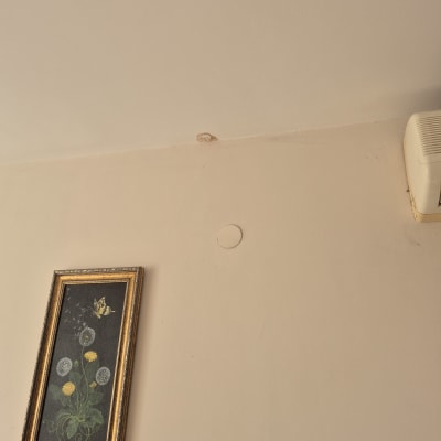 כתם רטיבות על קיר ליד תמונה ומזגן