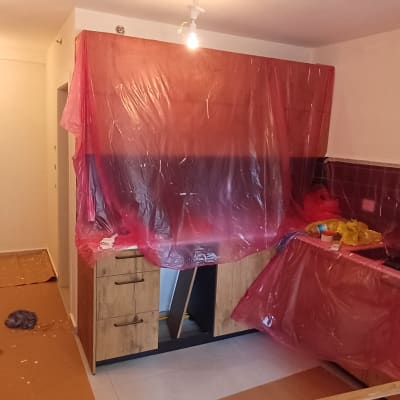 הגנה וכיסוי של ארונות מטבח ורצפה בניילון וקרטון במהלך עבודת צביעת דירה