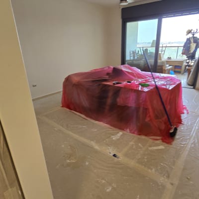 חדר עם רהיטים מכוסים בניילון לקראת צביעה